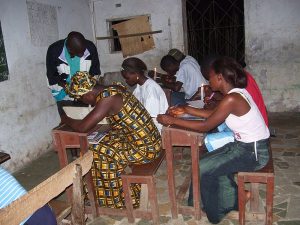 Estudiantes del Condado de Bong, Liberia, estudiando a la luz de una vela. Estos alumnos perdieron días de colegio durante la guerra civil de Liberia. Fotografía de dominio público proporcionada por la Agencia de los Estados Unidos para el Desarrollo Internacional (USAID por sus siglas en inglés).